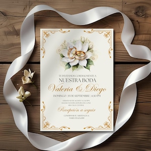 Puede incluir: Invitaci&oacute;n de boda con detalles dorados y dise&ntilde;o floral. La invitaci&oacute;n presenta los nombres "Valeria & Diego" y los detalles del evento. Una cinta blanca y flores enmarcan la invitaci&oacute;n sobre un fondo de madera.