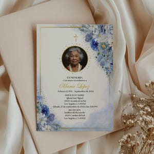 May include: A memorial card with a portrait of an elderly woman, framed in gold, with a cross and blue floral decorations. The card contains Spanish text detailing a memorial service, including dates and locations.