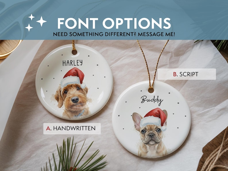May include: Two round white ceramic ornaments featuring illustrations of dogs wearing red Santa hats. One ornament displays the name Harley in a block font, and the other shows the name Buddy in a script font. Both include gold hanging strings.