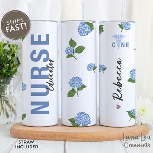 May include: Three white stainless steel tumblers with blue floral designs and personalized text. The tumblers are labeled "Nurse Educator", "Rebecca", and "CNE".