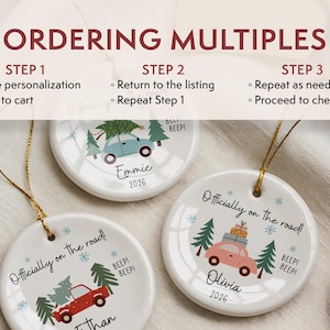 May include: Three round white ceramic ornaments with gold hanging strings. Each features a colourful car illustration, pine trees, snowflakes, and the text "Officially on the road!" and "BEEP! BEEP!". Names and the year 2026 are printed on each ornament.