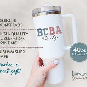 May include: White 40oz capacity tumbler with a handle, featuring the text "BCBA Emily" in blue, green, and pink. The tumbler has a silver lid and is labeled "Dishwasher Safe".