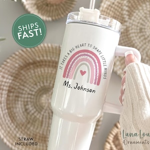 May include: White insulated tumbler with a handle, featuring a rainbow design and the text "It takes a big heart to shape little minds" and "Ms. Johnson". Includes a straw. The tumbler is a teacher-themed gift.