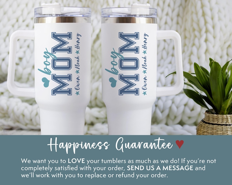 May include: Two white travel mugs with black handles. The mugs have a blue and white design that says "boy MOM" with a star and the name "Owen Noah Henry" underneath. The mugs are sitting on a white fuzzy surface.