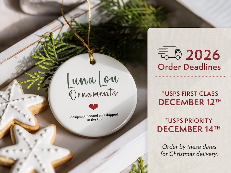 May include: A round white ceramic ornament with a gold hanging string. The text reads Luna Lou Ornaments with a small red heart and the text designed, printed and shipped in the US. Beside it is a sign with 2026 Order Deadlines for USPS shipping.