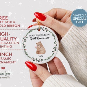 May include: A white ceramic ornament, 3 inches in diameter, with a gold string for hanging. The ornament features a watercolor illustration of a bear holding a flower, surrounded by a green wreath. Text reads "The Best Grandmas Become Great Grandmas" and "2025".
