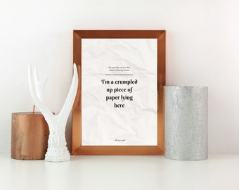 May include: A framed print with the text "I'm a crumpled up piece of paper lying here" in a gold frame, beside a white antler sculpture, and two candles, one copper and one silver.