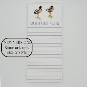 May include: A white notepad with horizontal black lines, featuring two mallard ducks at the top and the text GET YOUR DUCKS IN A ROW. A black outlined box on the left contains the text NEW VERSION! Same art, new size & style.