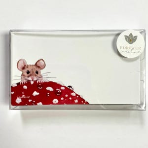 May include: A set of white notecards featuring a watercolor illustration of a brown mouse peeking over a red mushroom with white spots. The cards are packaged in a clear plastic box with a round sticker that says "Forever Caroline."