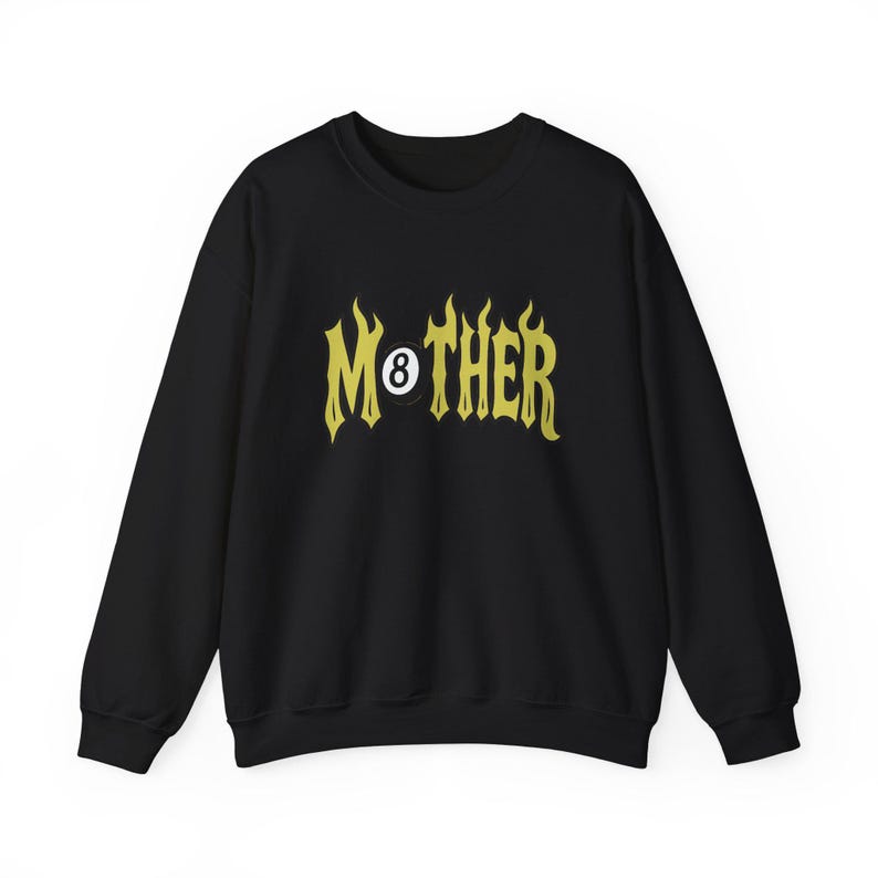 K&ouml;nnte beinhalten: Schwarzes Sweatshirt mit dem Wort "MOTHER" in gelber, flammenartiger Schrift. Die Zahl 8 ist in das Design integriert. Das Sweatshirt hat einen Rundhalsausschnitt und lange &Auml;rmel.