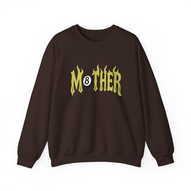 K&ouml;nnte beinhalten: Ein dunkelbraunes Sweatshirt mit dem Wort "MOTHER" in gelber, flammenartiger Schrift. Der Buchstabe "O" wird durch eine Acht-Ball ersetzt. Das Sweatshirt hat lange &Auml;rmel und einen Rundhalsausschnitt.