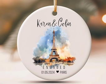 May include: White ceramic ornament with a watercolor painting of the Eiffel Tower in Paris, France. The ornament says "Karen & Colin Engaged 01.05.2024 ♥ PARIS".