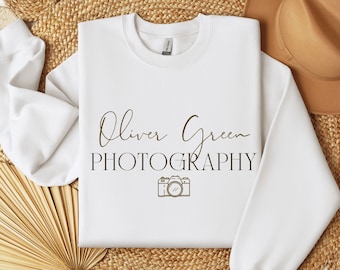 May include: White sweatshirt with a brown graphic design that says "Oliver Green Photography" with a camera icon.