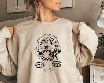 May include: A beige sweatshirt with a black and white illustration of a dog with the name "Ginger" printed below the image.