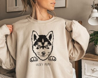 Op de afbeelding: Een beige sweatshirt met een zwart-witte illustratie van een husky puppy met de tekst "Husky Mama" eronder.