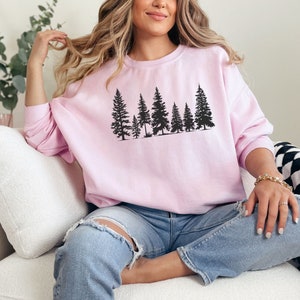 May include: A pink sweatshirt with a black silhouette of a row of pine trees printed on the front.