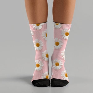 May include: A pair of pink socks with a white daisy pattern. The socks are made of a soft, comfortable material and have a black toe and heel.