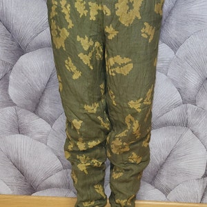 May include: Green and gold camouflage pants with a drawstring waist. The pants are made of a soft, comfortable fabric and have a relaxed fit.