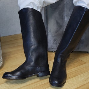 May include: A pair of black leather riding boots with a pointed toe and a low heel.