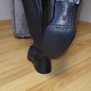 May include: Black leather riding boots with a rubber sole and a textured pattern. The sole has a size 42 printed on it.