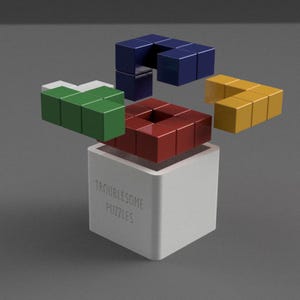 May include: A white cube with the text "Troublesome Puzzles" contains a red square puzzle. Detached puzzle pieces in blue, green, and yellow surround it. The image depicts a brain teaser puzzle.