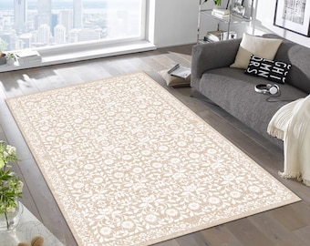 May include: A rectangular area rug featuring a repeating white floral and vine pattern set against a light tan background. The design includes intricate blossoms and scrolling leaves arranged in a symmetrical grid, finished with a decorative border.