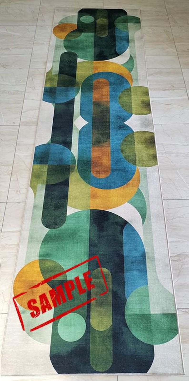 May include: A rectangular rug with an abstract design featuring overlapping shapes in shades of green, blue, orange, and yellow on a white background. The rug has a geometric pattern and a "SAMPLE" stamp in red.