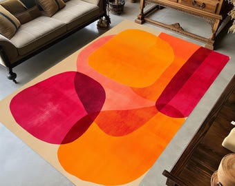 May include: A rectangular area rug featuring a beige background with large, overlapping abstract shapes in vibrant shades of orange, bright red, and deep magenta. The design includes rounded forms and straight bands, creating a layered effect.