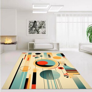 May include: A rectangular area rug featuring a cream background with a geometric pattern of circles, lines, and rectangles in shades of teal, orange, black, and yellow. The design includes various solid shapes and striped elements arranged across the surface.