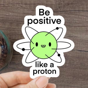 May include: A green and black sticker with a cartoon atom and the text "Be positive like a proton".