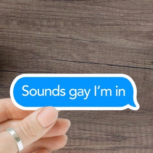 Może przedstawiać: Niebieska i biała naklejka z tekstem "Sounds gay I'm in" na drewnianej powierzchni.
