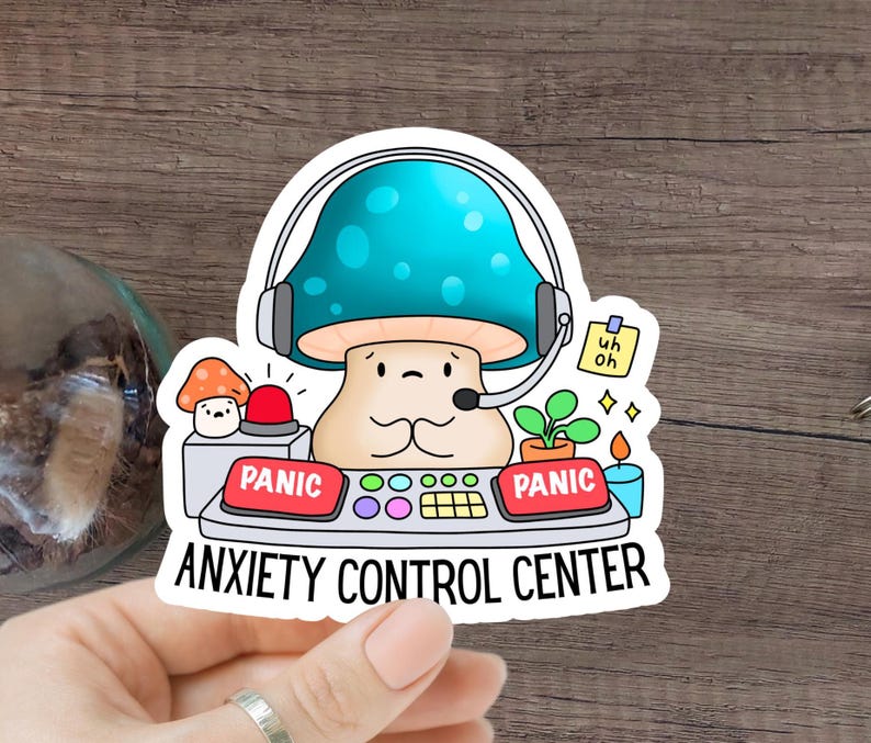 May include: A sticker featuring a cartoon mushroom wearing a headset and sitting at a control panel with buttons labeled "Panic". The text "Anxiety Control Center" is below the panel.