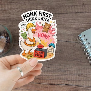 Könnte beinhalten: Ein farbenfroher Aufkleber mit einer Cartoon-Gans, die einen Bauhelm und eine Weste trägt, mit dem Text "HONK FIRST, THINK LATER". Der Aufkleber enthält einen roten Knopf mit der Aufschrift "DO NOT PRESS" und weitere Elemente.