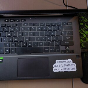 May include: A black laptop computer with a sticker that reads "If my mouth doesn't say it my face definitely will".