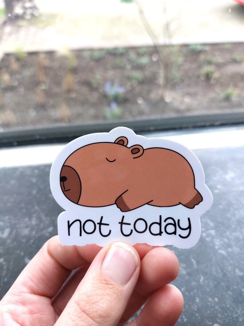 Puede incluir: Una pegatina blanca con una capibara marr&oacute;n de dibujos animados durmiendo con el texto "not today" debajo.