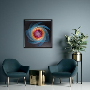 Op de afbeelding: Een ingelijst abstract kunstwerk met een kleurrijk spiraalontwerp in tinten blauw, roze en oranje tegen een zwarte achtergrond. Het kunstwerk wordt getoond aan een muur met twee tealblauwe fauteuils en een gouden bijzettafel.