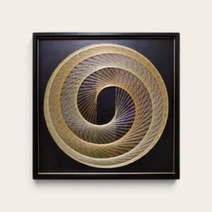 May include: A square wall art piece featuring a black background with a circular string art design. The design is created with gold-coloured thread arranged in a spiral pattern, forming a geometric vortex effect inside a black wooden frame.