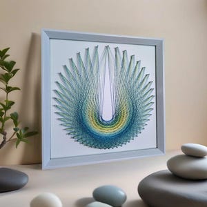 May include: A framed string art piece with a blue, green, and yellow geometric design. The design is a circle with a U-shaped pattern in the center.