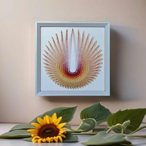May include: A framed string art piece with a white background and a colorful, geometric design. The design is a circle with a U-shaped pattern in the center. The colors are red, orange, yellow, and brown.