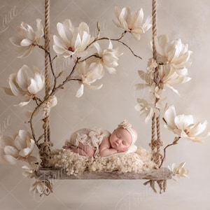 Puede incluir: Un bebé recién nacido duerme plácidamente en un columpio rústico de madera adornado con grandes flores de magnolia color crema. El columpio está suspendido por cuerdas y se encuentra sobre un fondo suave y neutro, creando una escena serena y delicada.