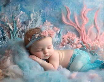 May include: A sleeping baby wearing a blue and silver mermaid tail costume and a flower crown, lying on a blue and white fluffy surface with pink and blue floral decorations.