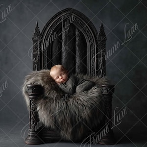 May include: A newborn baby sleeping on a faux fur blanket in a black throne-like chair. The chair has a high back and intricate carvings.