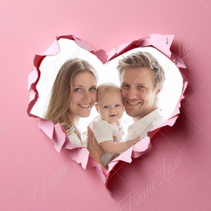 May include: A family of three, a mother, father, and baby, are smiling and looking at the camera. They are peeking through a heart-shaped hole in a pink background.