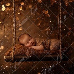 Può includere: Un bambino addormentato avvolto in un tessuto marrone è sdraiato su un cuscino in un'altalena di legno. L'altalena è sospesa da un ramo d'albero con foglie dorate e luci scintillanti.