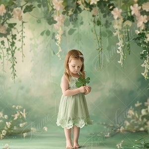 May include: A young girl wearing a light green dress stands in front of a green and white floral backdrop. She is holding a four-leaf clover in her hand.
