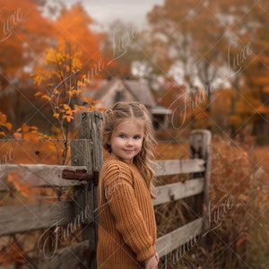 Puede incluir: Una niña pequeña con cabello rubio que lleva un suéter marrón se para junto a una cerca de madera en un campo de hojas de otoño.