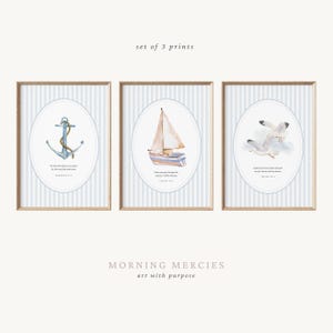 May include: Set of three framed prints with nautical themes. Each print features a watercolor illustration inside an oval frame against a blue and white striped background. The images include an anchor, a sailboat, and two seagulls.
