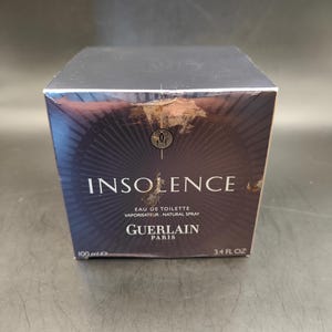 Puede incluir: Una caja negra con letras doradas para un frasco de 100 ml de Insoence Eau de Toilette de Guerlain Paris. La caja tiene un dise&ntilde;o negro y dorado con un patr&oacute;n de rayos de sol.