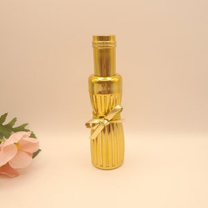 May include: A gold bottle with a gold ribbon bow and the text "Smith + Drew" engraved on the side.