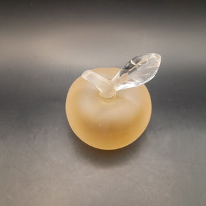 May include: A frosted glass apple shaped bottle with a clear glass stem and leaf.